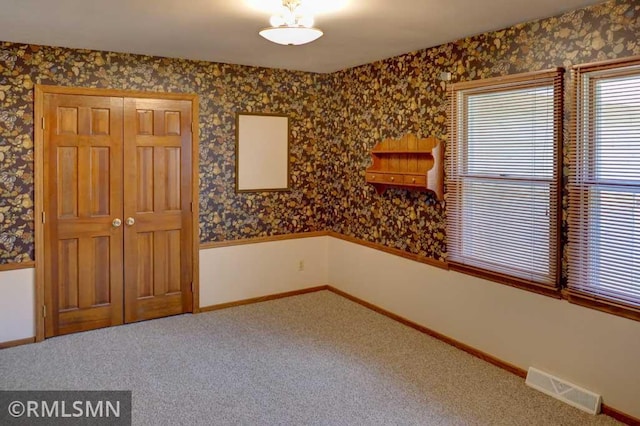 unfurnished room with visible vents, carpet flooring, baseboards, and wallpapered walls