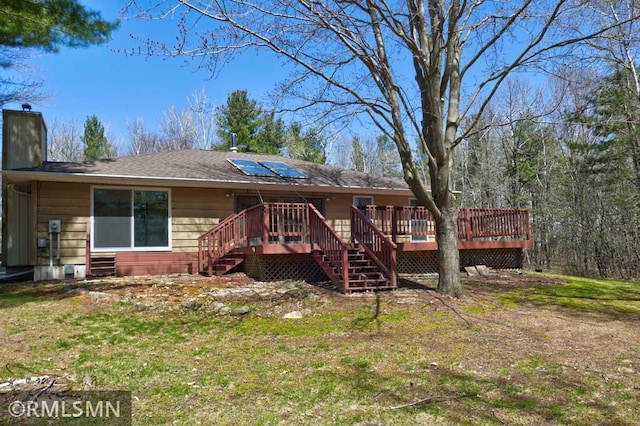 back of house with stairs, a chimney, a yard, and a deck
