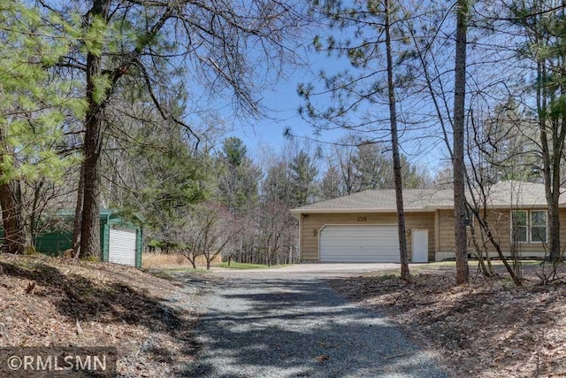 view of side of property with a garage and gravel driveway