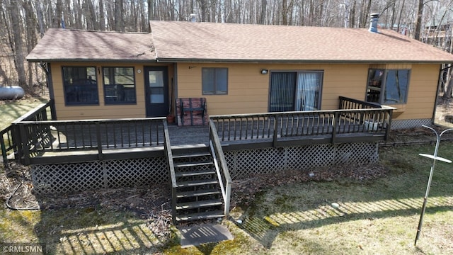 back of house with a shingled roof, a deck, and stairway