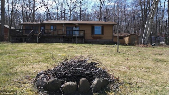 back of property featuring a yard, an outbuilding, a wooden deck, and a shed
