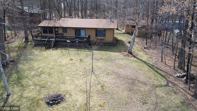 view of front of house with roof with shingles, a deck, and a front yard