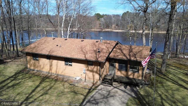 back of house featuring a lawn, a water view, roof with shingles, and central AC unit