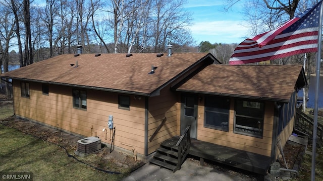 rear view of house with a shingled roof and central air condition unit