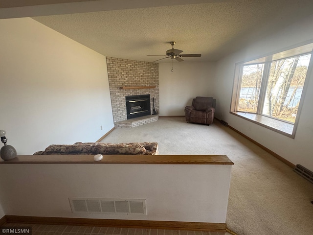 unfurnished living room featuring visible vents, carpet floors, a fireplace, baseboards, and a ceiling fan