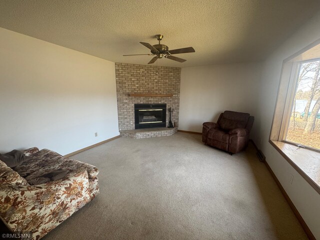 carpeted living area with baseboards, a ceiling fan, a textured ceiling, and a fireplace