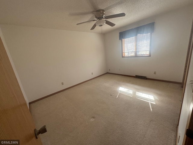 empty room featuring a ceiling fan, a textured ceiling, visible vents, baseboards, and carpet