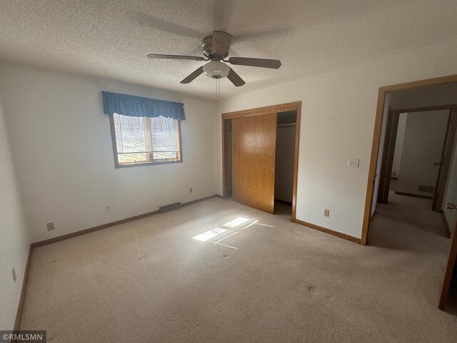 unfurnished bedroom featuring a textured ceiling, baseboards, carpet, and a closet