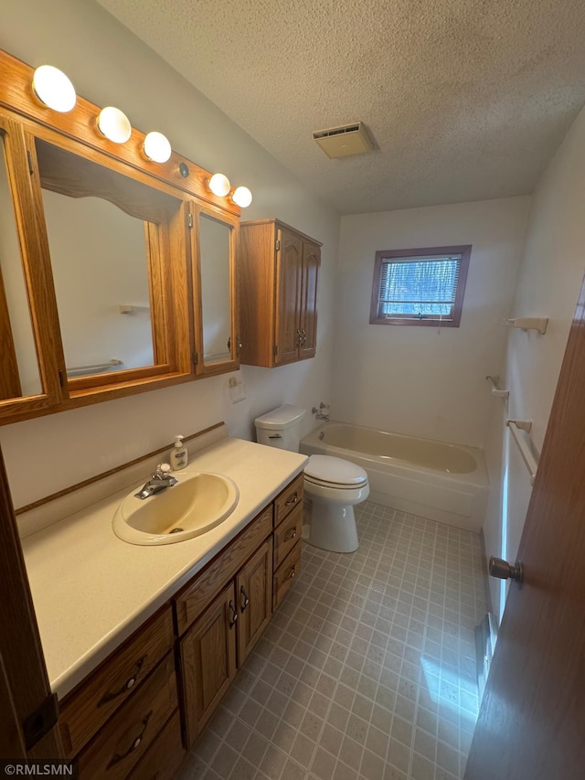 full bathroom with visible vents, vanity, toilet, a tub, and a textured ceiling