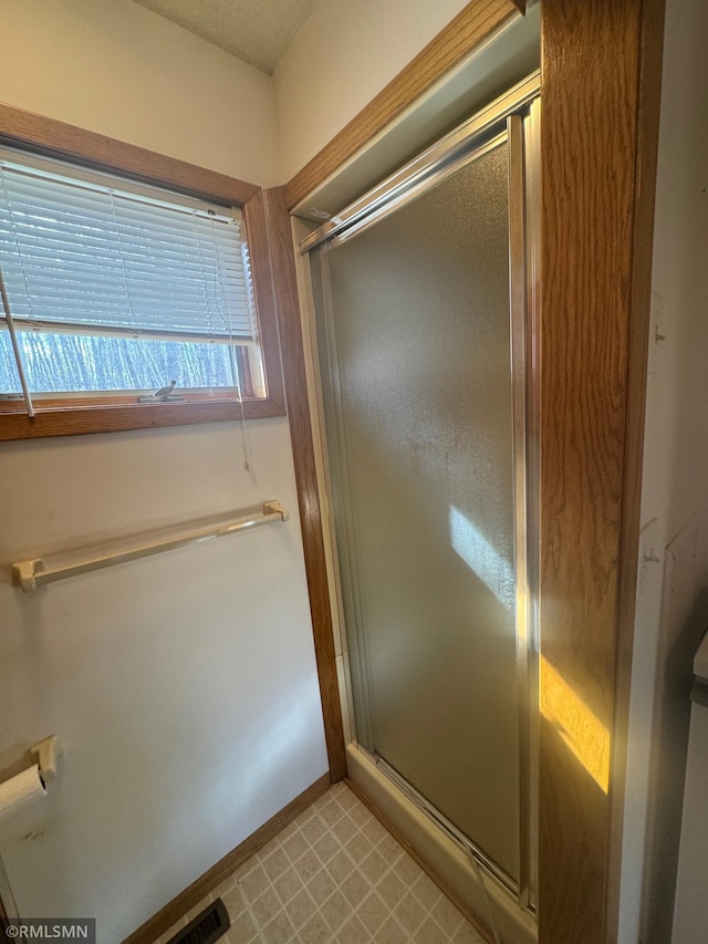 full bathroom with baseboards, tile patterned floors, and a shower stall