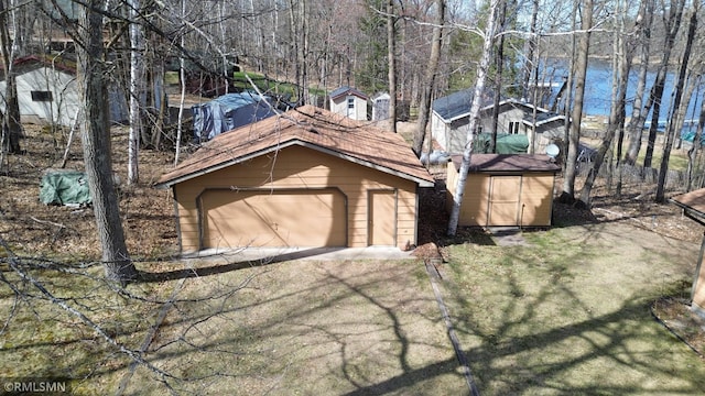 view of side of home featuring a garage, an outbuilding, a water view, and a shed