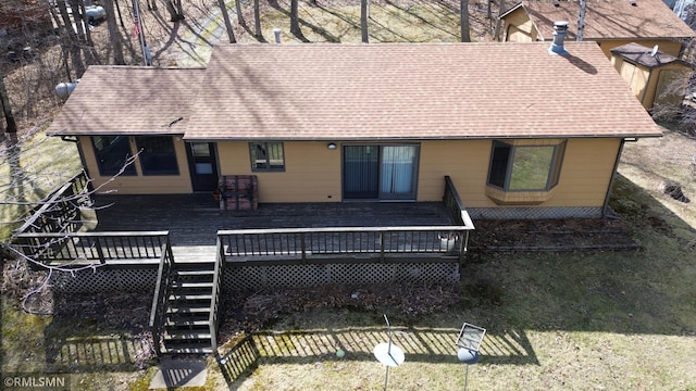 rear view of house with roof with shingles, a wooden deck, and a yard