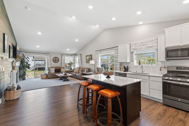kitchen with appliances with stainless steel finishes, a sink, a center island, open floor plan, and white cabinetry