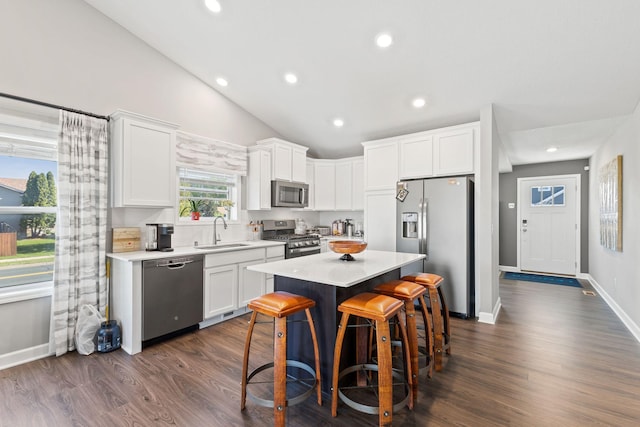 kitchen with stainless steel appliances, a sink, white cabinetry, a center island, and light countertops