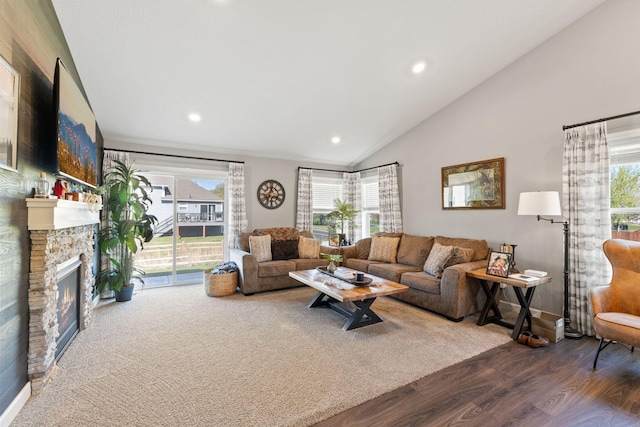 living room featuring dark wood-style floors, lofted ceiling, healthy amount of natural light, recessed lighting, and a stone fireplace