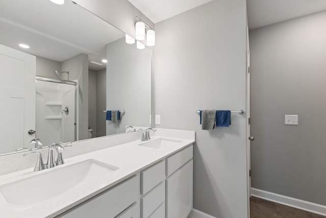 bathroom with a shower, baseboards, double vanity, toilet, and recessed lighting