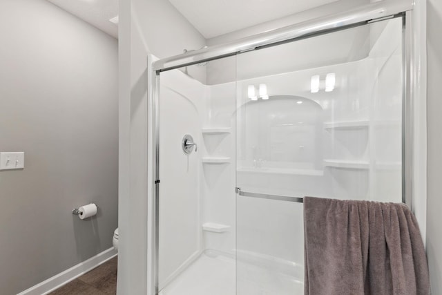 bathroom featuring a stall shower, toilet, and baseboards