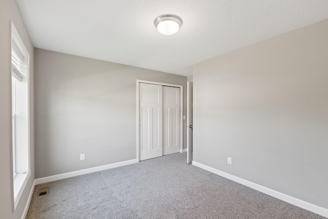 unfurnished bedroom featuring carpet, baseboards, and a closet