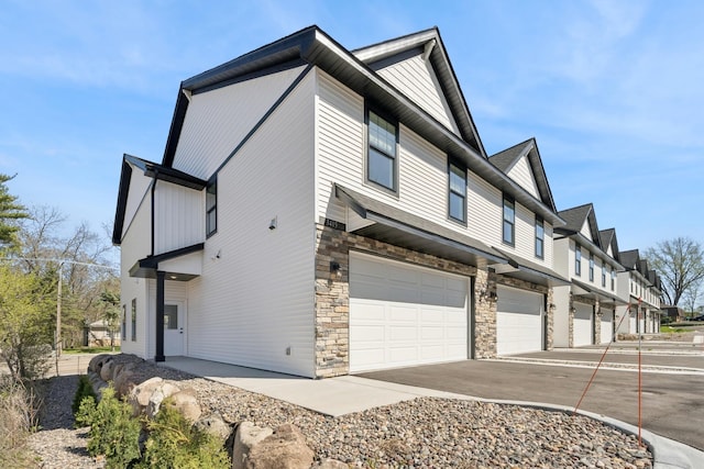 view of property exterior with a garage, driveway, and stone siding