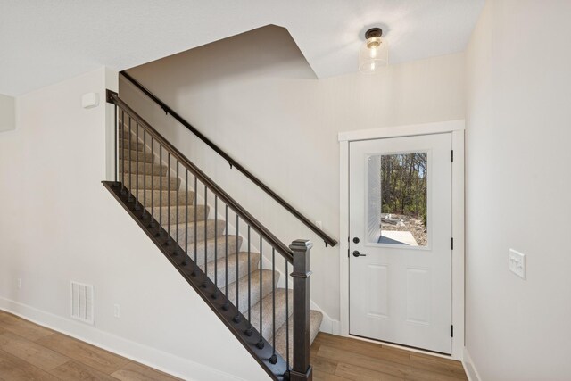 entryway featuring baseboards, stairs, hardwood / wood-style floors, and visible vents