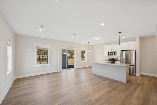 kitchen featuring baseboards, an island with sink, white cabinets, light wood-style flooring, and stainless steel appliances