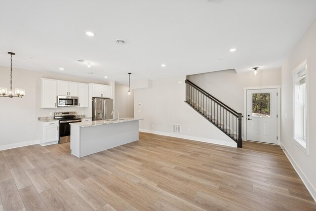 kitchen with appliances with stainless steel finishes, light wood finished floors, a sink, and visible vents