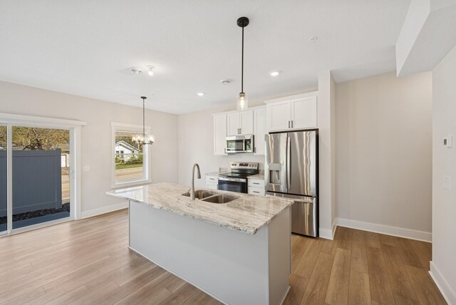 kitchen with a sink, light wood finished floors, appliances with stainless steel finishes, and white cabinetry