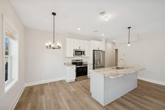 kitchen with white cabinets, appliances with stainless steel finishes, a sink, and light wood finished floors