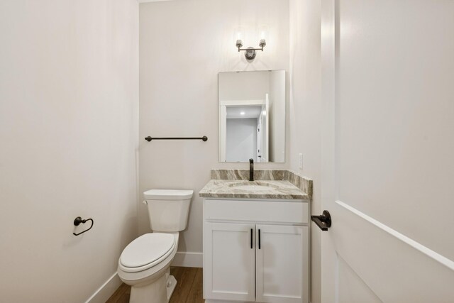 bathroom featuring vanity, baseboards, toilet, and wood finished floors