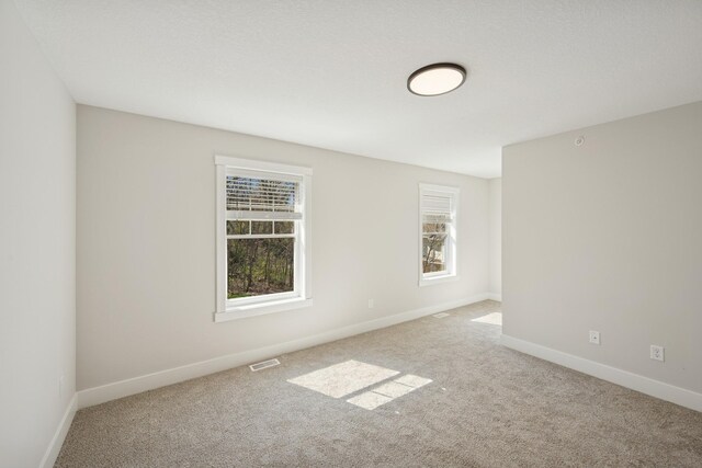 empty room with carpet flooring, baseboards, and visible vents