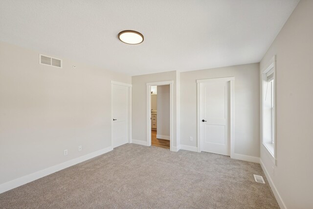 unfurnished bedroom with visible vents, baseboards, and light carpet