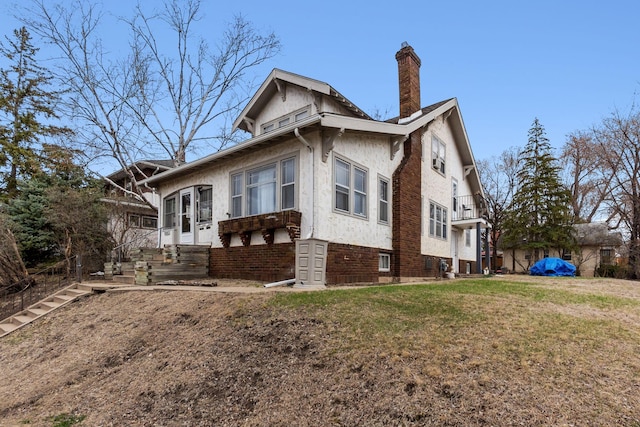 view of side of property featuring a chimney, a yard, and stucco siding