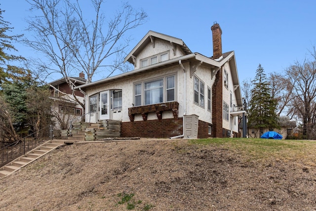 bungalow-style house with a chimney and stucco siding