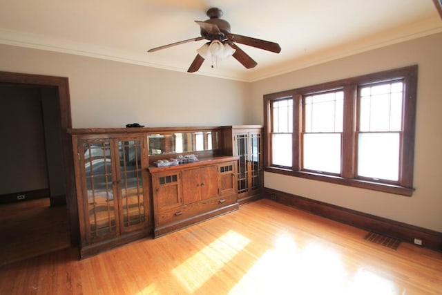 unfurnished room with crown molding, ceiling fan, visible vents, and light wood-type flooring