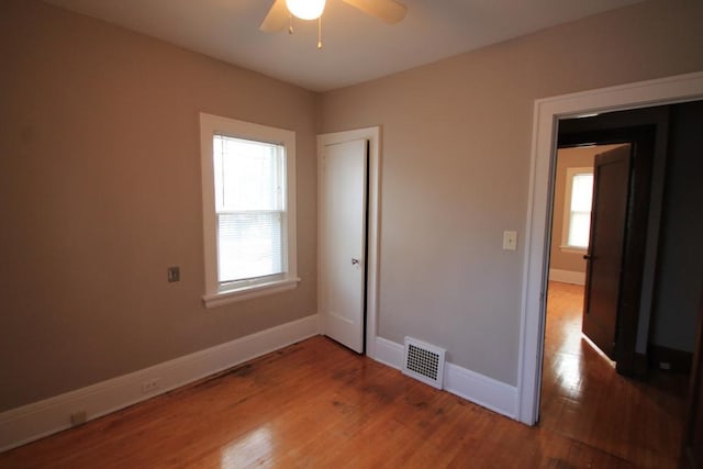 unfurnished bedroom with baseboards, a ceiling fan, wood finished floors, and visible vents