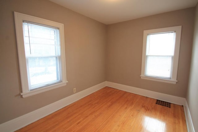 empty room with baseboards, a wealth of natural light, and visible vents