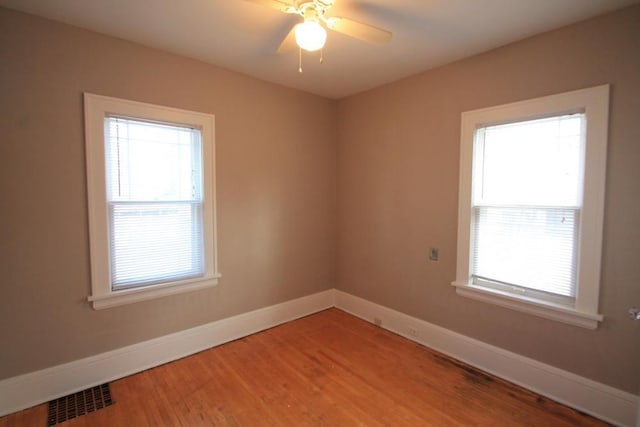 empty room featuring baseboards, visible vents, a wealth of natural light, and light wood-style floors