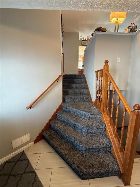 9007 Hampshire Ave N, Brooklyn Park, MN 55445 - staircase with visible vents, baseboards, and tile patterned flooring