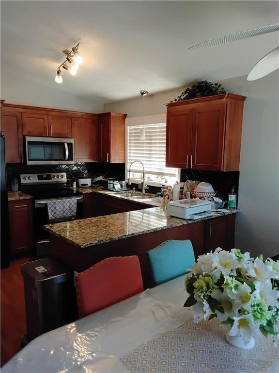 9007 Hampshire Ave N, Brooklyn Park, MN 55445 - kitchen with track lighting, stone countertops, tasteful backsplash, a sink, and appliances with stainless steel finishes