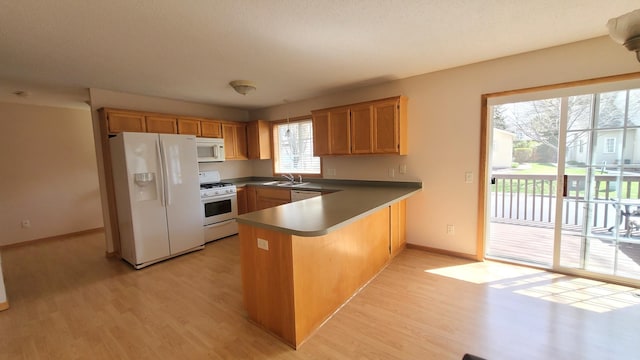 44 Willow Way, Farmington, MN 55024 - kitchen featuring white appliances, a peninsula, light wood finished floors, dark countertops, and baseboards