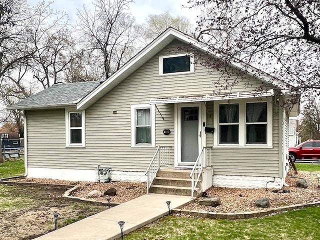bungalow-style home with roof with shingles