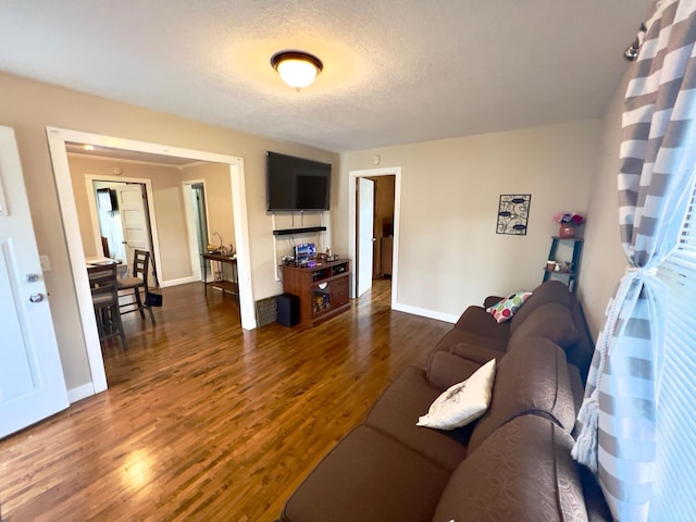 living area featuring baseboards, dark wood-style flooring, and a textured ceiling
