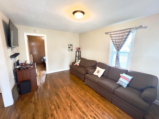 living area with baseboards, a textured ceiling, and wood finished floors