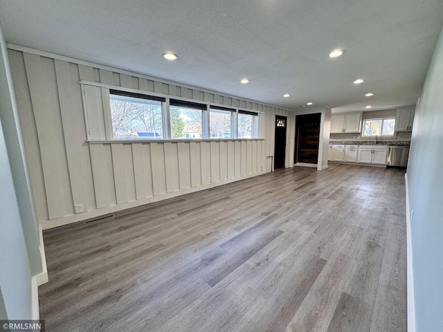 unfurnished living room featuring a sink, recessed lighting, wood finished floors, and visible vents