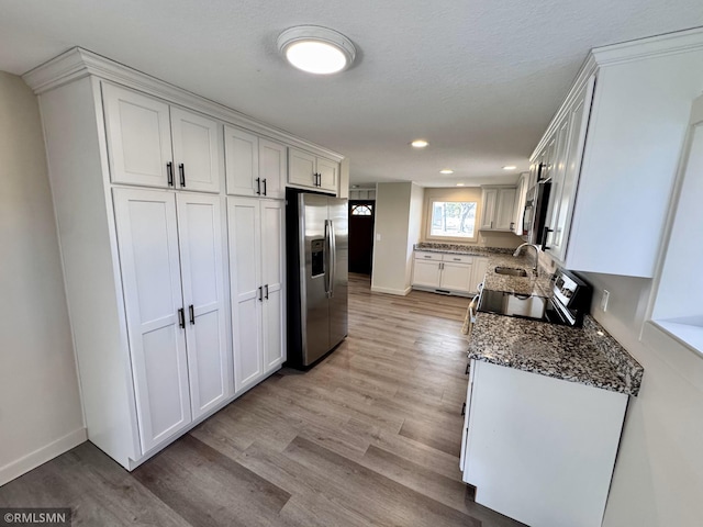 kitchen featuring light wood-style floors, recessed lighting, dark stone counters, white cabinets, and appliances with stainless steel finishes