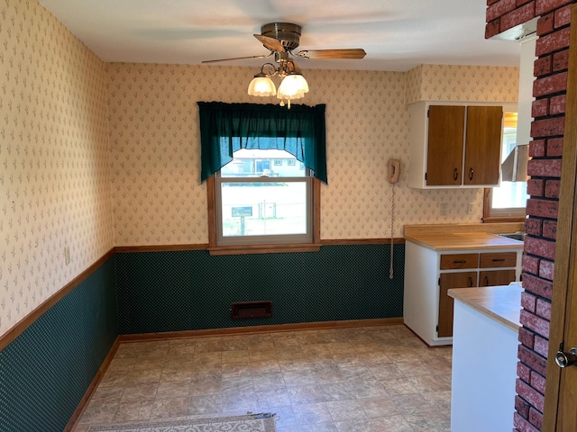 kitchen with a ceiling fan, hanging light fixtures, light countertops, baseboards, and wallpapered walls