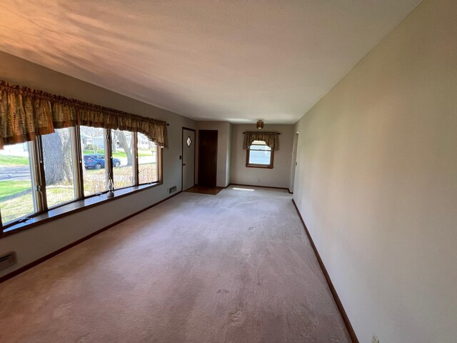 unfurnished living room featuring baseboards and light colored carpet