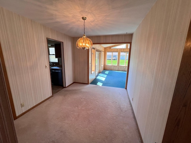 interior space featuring baseboards, plenty of natural light, light colored carpet, and a chandelier