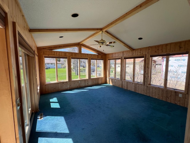 unfurnished sunroom featuring carpet, lofted ceiling, and wooden walls