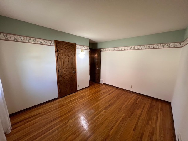 unfurnished bedroom featuring wood finished floors and visible vents